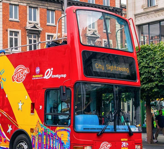 Red double-decker bus for City Sightseeing Dublin tour on a street with historic buildings.