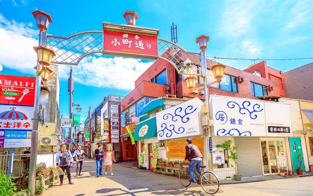 Komachi Street entrance with people walking and cycling in Kamakura, Japan.