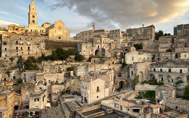 Sassi di Matera ancient stone buildings and church at sunset during E-Vespa tour.