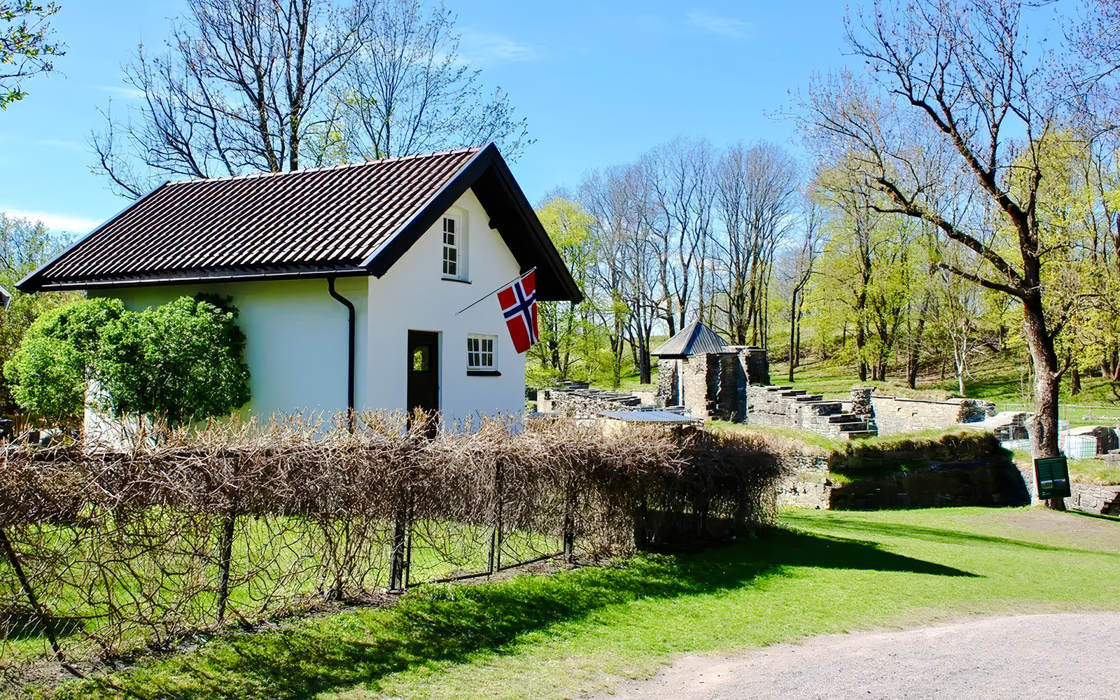 White house with Norwegian flag near medieval ruins on Oslofjord island.