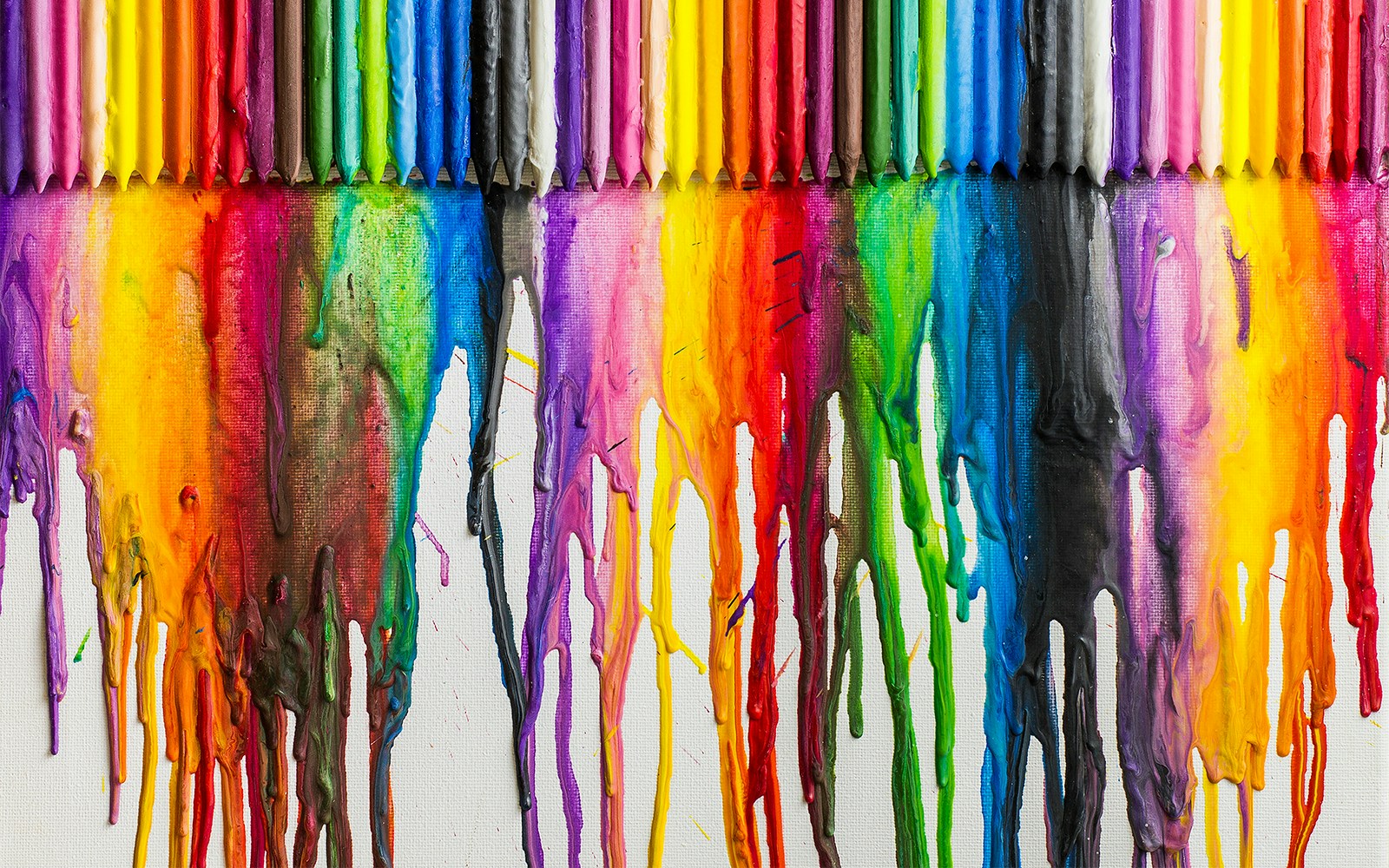 Melted crayons dripping down white paper creating colorful abstractions.