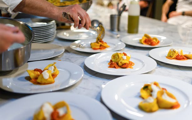 Pasta being plated during a cooking class in Milan.