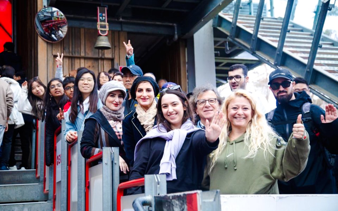 Group of tourists on a Half Day Blue Mountains Tour, standing on a platform, smiling and waving.
