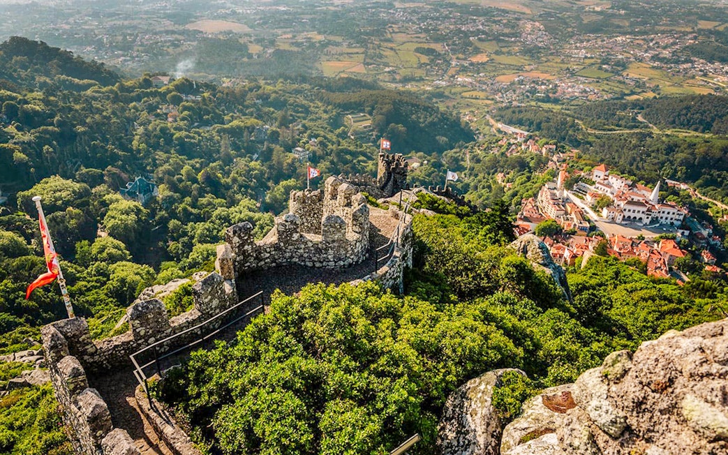 Aerial view of Moorish Castle in Sintra, Portugal, with lush greenery and historic stone walls.