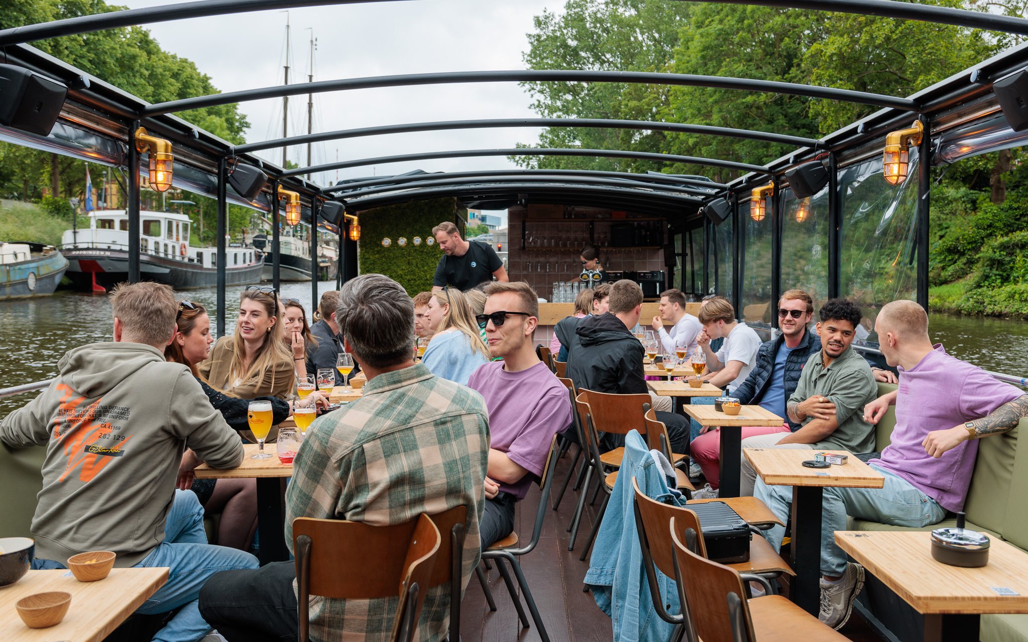 Groningen boat tour with people enjoying drinks at a terrace bar on the canal.