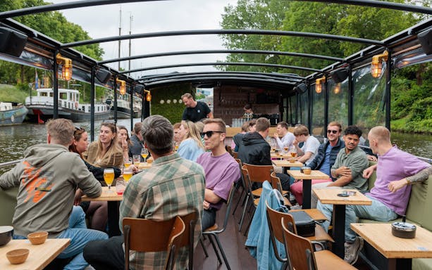 Groningen boat tour with people enjoying drinks at a terrace bar on the canal.