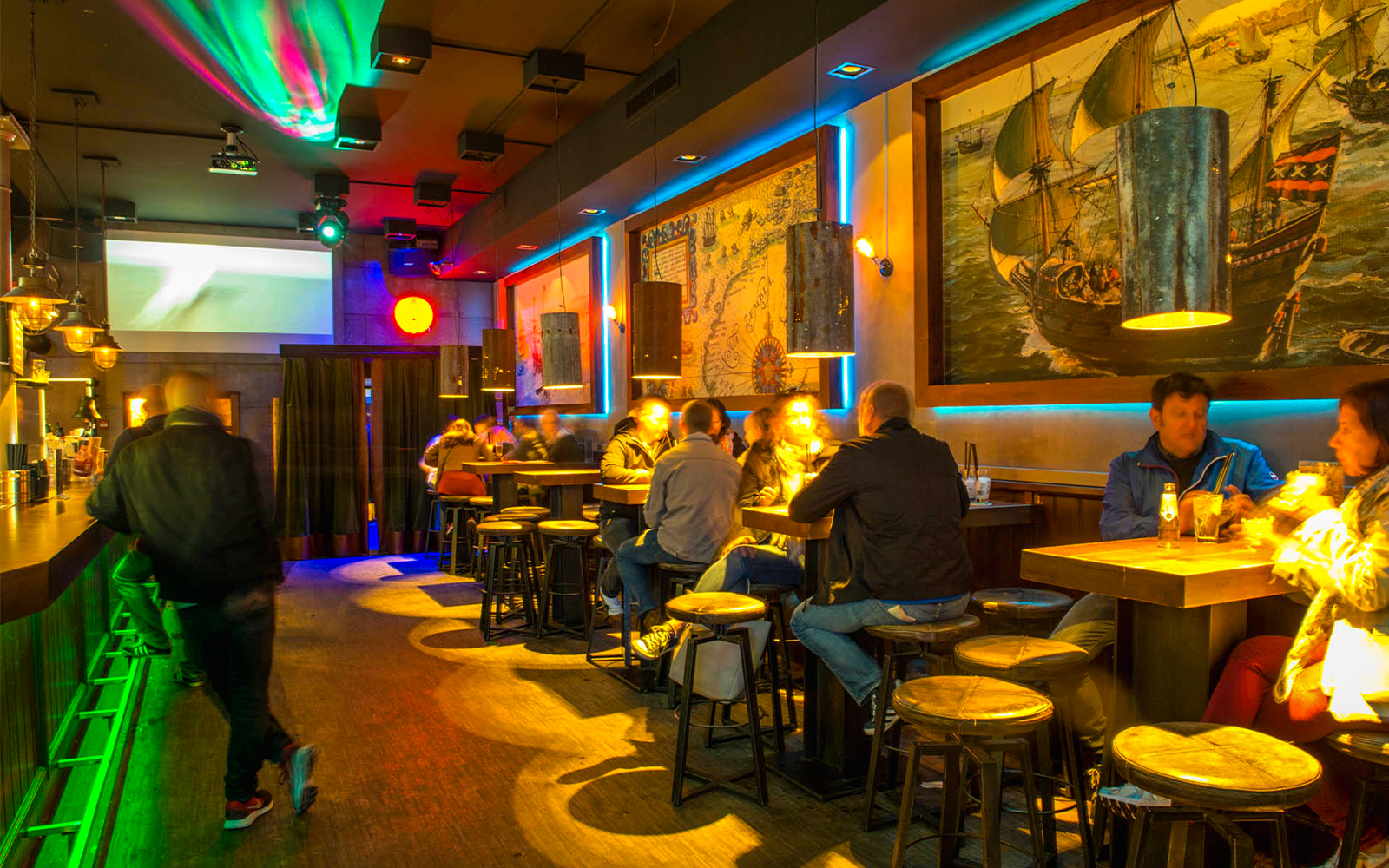Patrons enjoying drinks at Icebar Amsterdam with vibrant lighting and nautical decor.