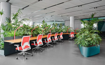 Workspace with red chairs and plants at MOL Campus interior.
