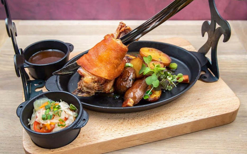 Roasted pork knuckle with potatoes and greens at Hungarian Royal Guard exhibition in Budapest.