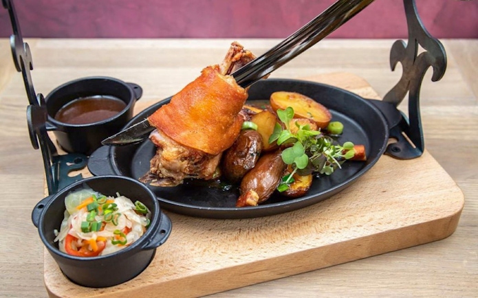 Roasted pork knuckle with potatoes and greens at Hungarian Royal Guard exhibition in Budapest.