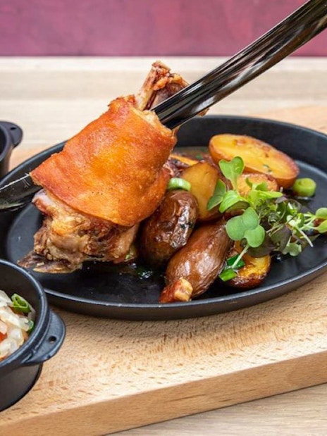 Roasted pork knuckle with potatoes and greens at Hungarian Royal Guard exhibition in Budapest.