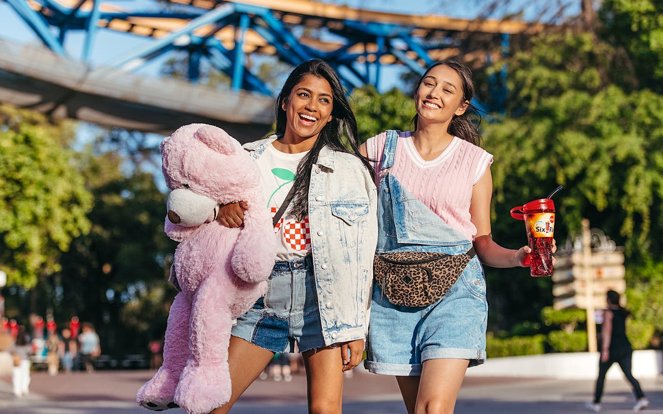 Visitors enjoying Six Flags Magic Mountain with a plush toy and branded drink cup.
