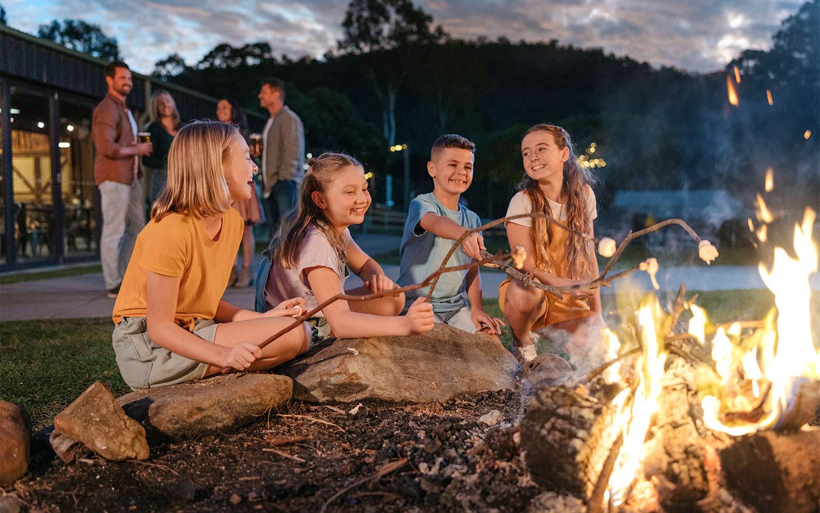 Children roasting marshmallows by a campfire at Paradise Country.