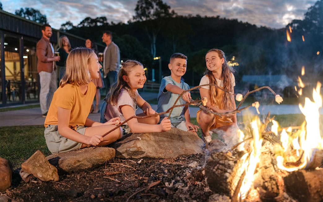 Children roasting marshmallows by a campfire at Paradise Country.