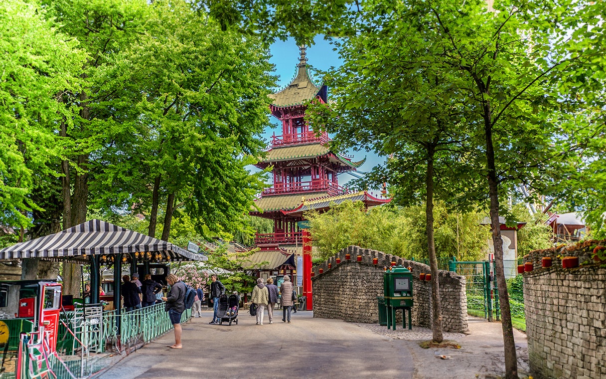 Pagoda temple in Tivoli Gardens, Copenhagen, surrounded by trees and visitors exploring the area.