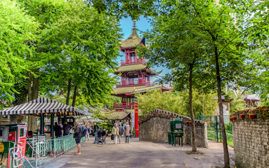 Pagoda temple in Tivoli Gardens, Copenhagen, surrounded by trees and visitors exploring the area.