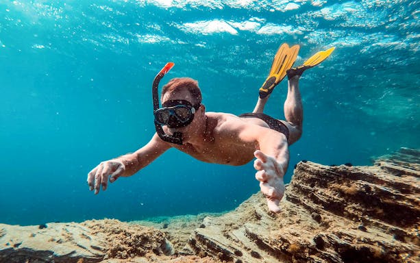 Snorkeler exploring underwater near Santorini on a luxury catamaran cruise.