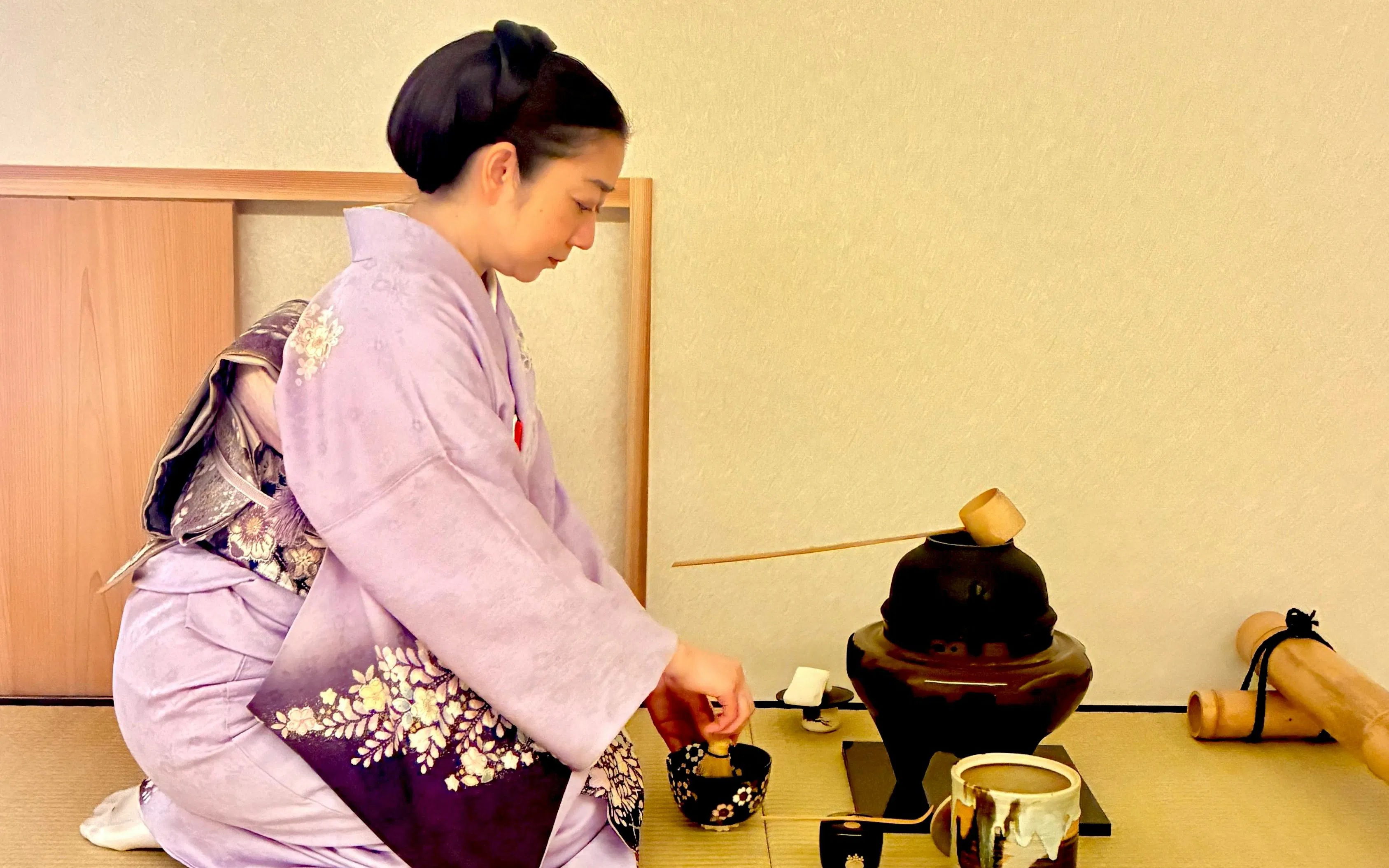 Woman in kimono performing traditional tea ceremony in Kyoto, Japan.