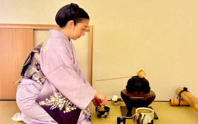 Woman in kimono performing traditional tea ceremony in Kyoto, Japan.