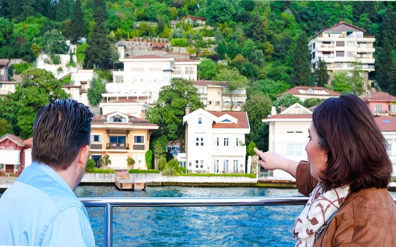 Tourists on a Bosphorus cruise viewing waterfront villas in Istanbul.