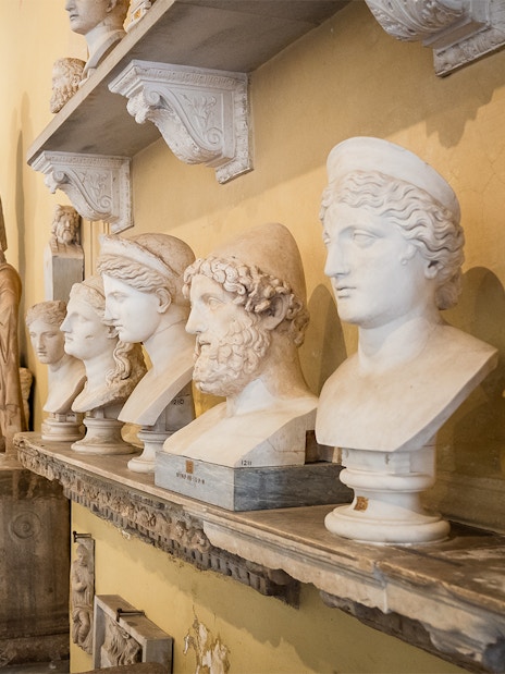 Visitors walking through Chiaramonti Museum hall with classical sculptures, Vatican Museums.