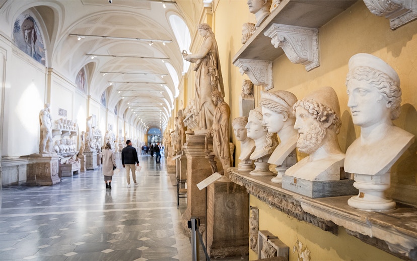 Visitors walking through Chiaramonti Museum hall with classical sculptures, Vatican Museums.