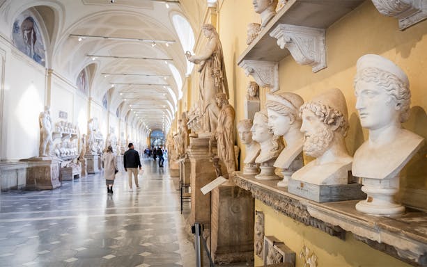 Visitors walking through Chiaramonti Museum hall with classical sculptures, Vatican Museums.
