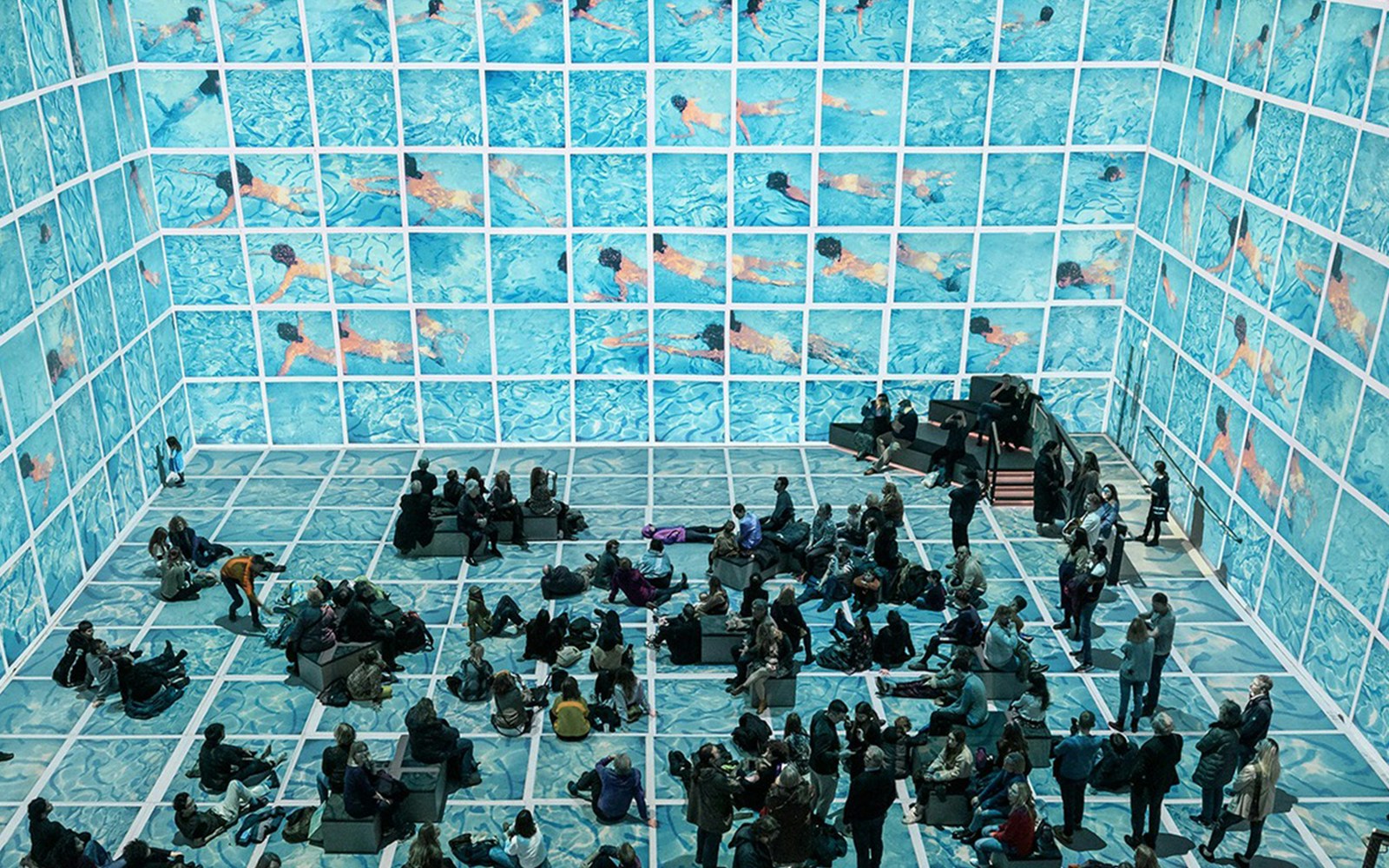 Visitors viewing immersive David Hockney exhibit "Bigger & Closer" with swimming pool imagery.