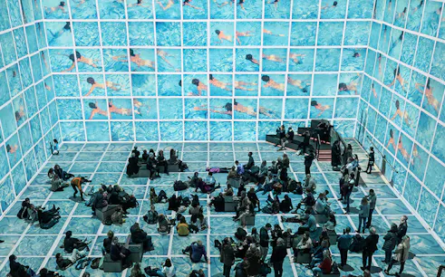 Visitors viewing immersive David Hockney exhibit "Bigger & Closer" with swimming pool imagery.
