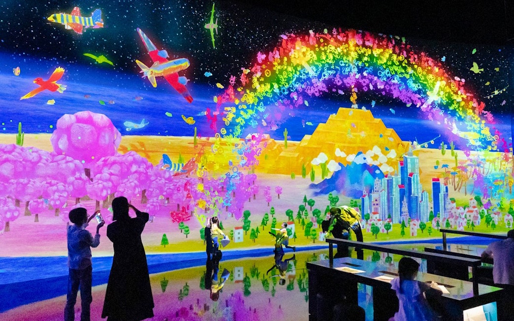 Colorful digital art display with rainbow, planes, and cityscape at Sketch Umwelt world exhibit.