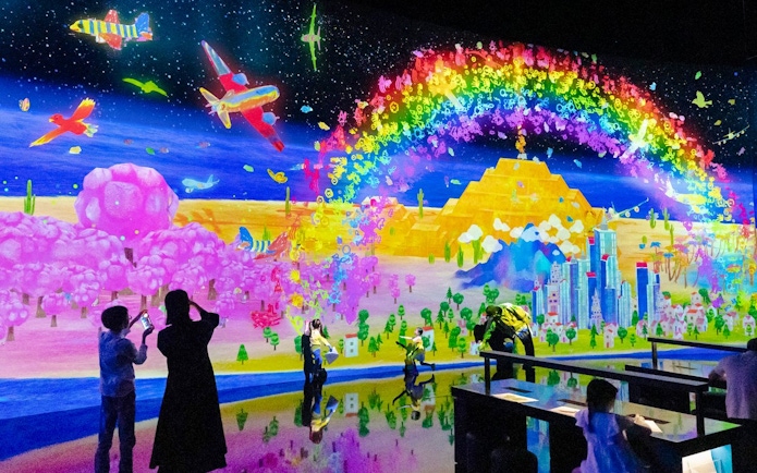 Colorful digital art display with rainbow, planes, and cityscape at Sketch Umwelt world exhibit.