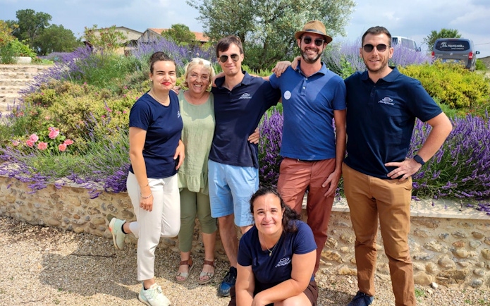 Group of people smiling in a lavender field during a tour in Sault, France.