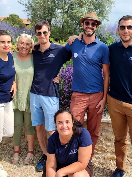 Group of people smiling in a lavender field during a tour in Sault, France.