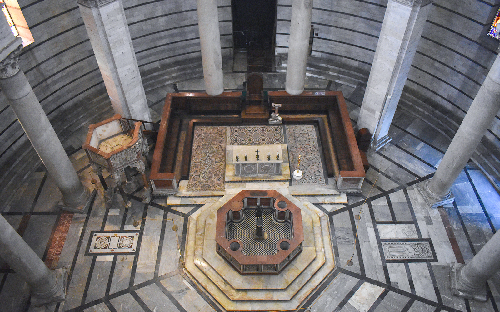 Tourists exploring the historic Pisa Baptistery featuring the unique octagonal font in Pisa, Italy