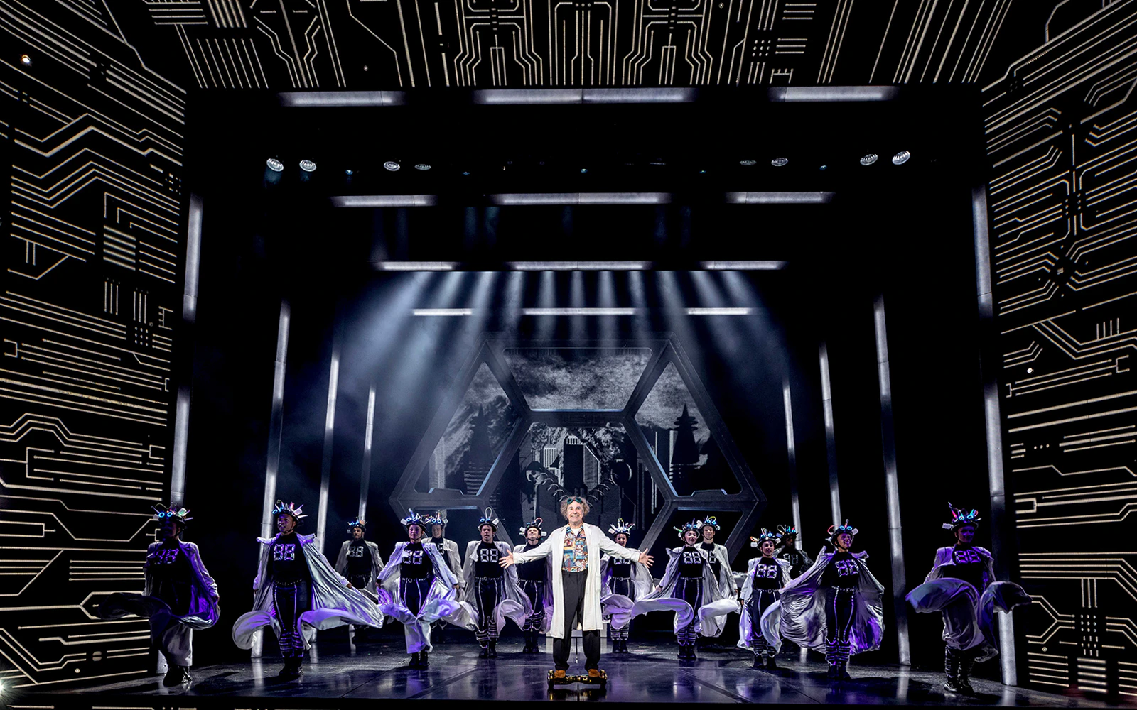 Stage performance of "Back to the Future" with actors in futuristic costumes and dynamic lighting.