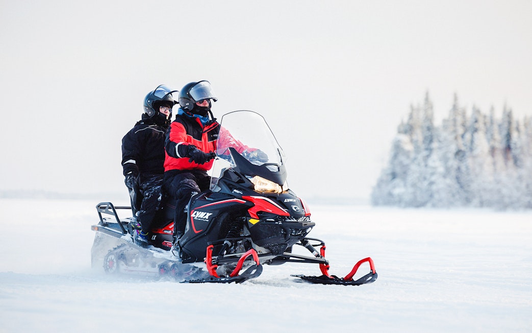 Snowmobile safari in snowy Lapland landscape.