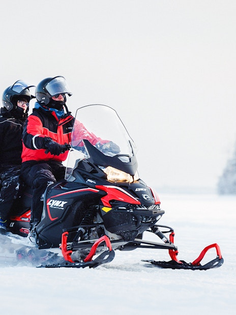 Snowmobile safari in snowy Lapland landscape.