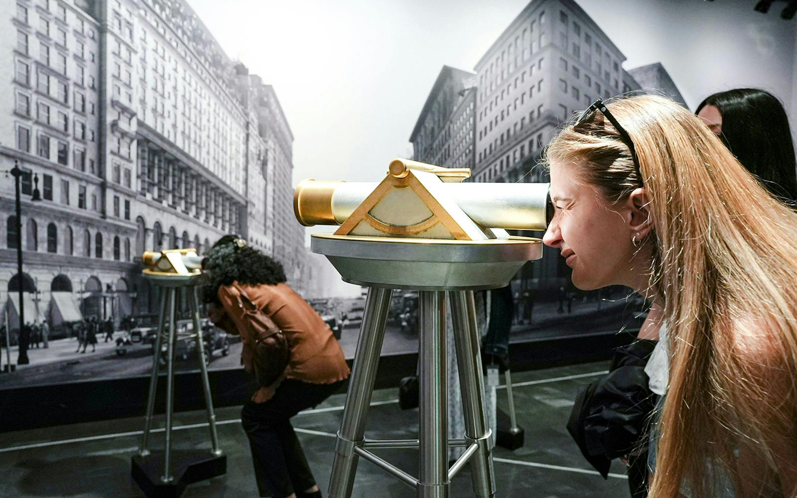 Visitors using telescopes at Empire State Building exhibit in New York City.
