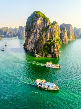 Halong Bay cruise ship sailing past limestone karsts in Vietnam.