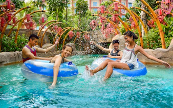 People enjoying the Lazy River at Adventure Cove waterpark, surrounded by tropical plants.