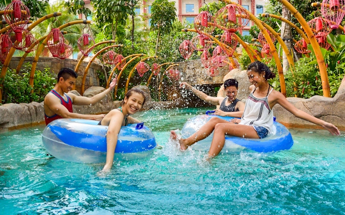 People enjoying the Lazy River at Adventure Cove waterpark, surrounded by tropical plants.