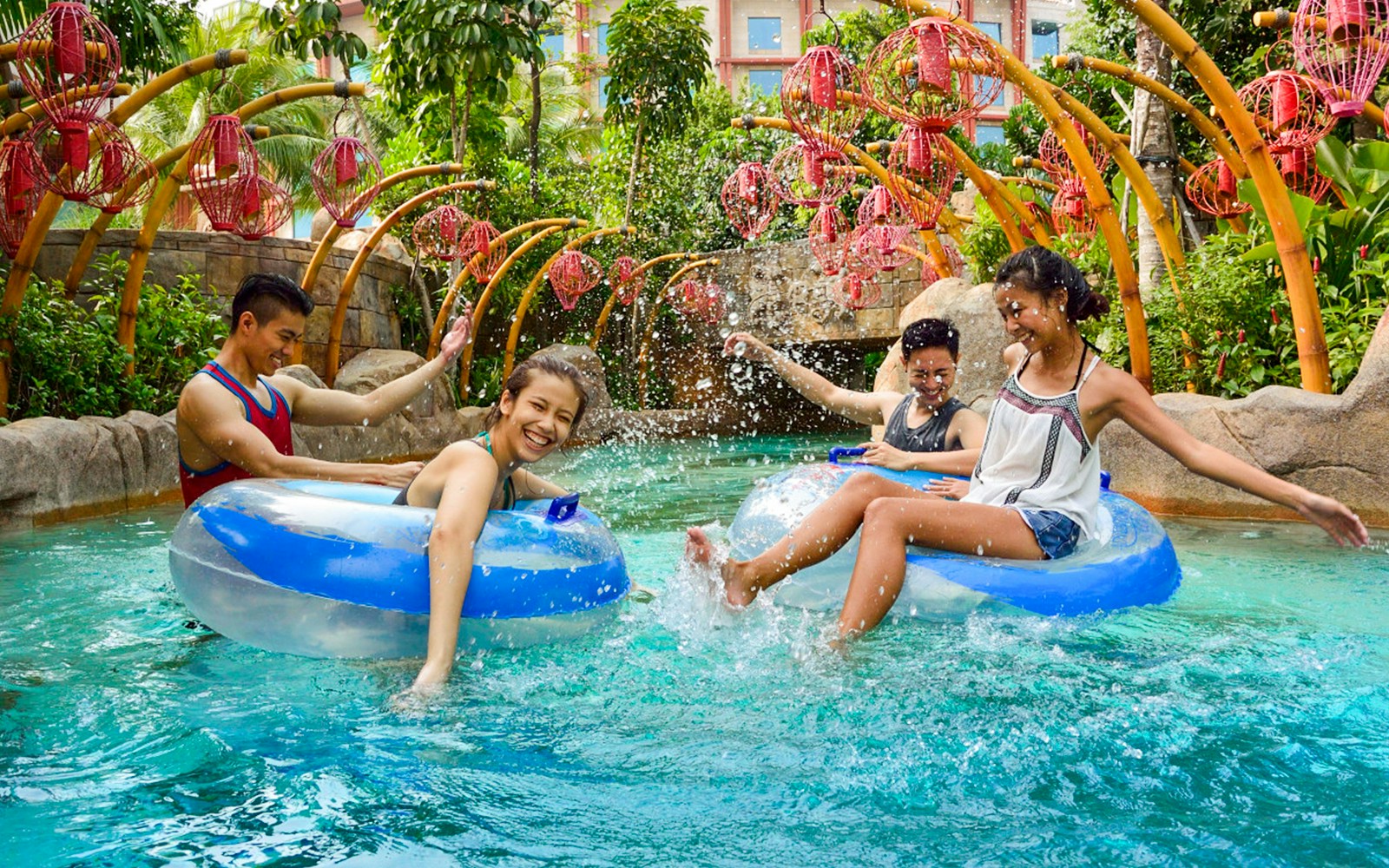 People enjoying the Lazy River at Adventure Cove waterpark, surrounded by tropical plants.