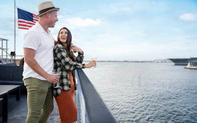 Couple enjoying drinks on a San Diego dinner cruise with ocean view.
