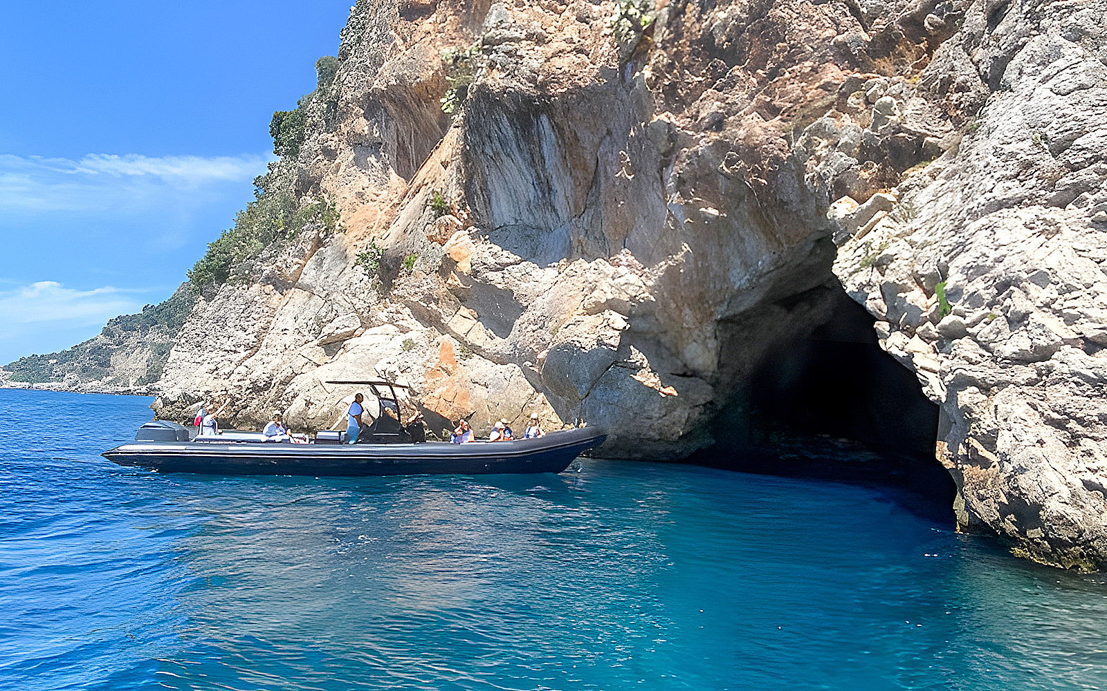 Boat near rocky cliffs and cave on Nice to Monaco tour.