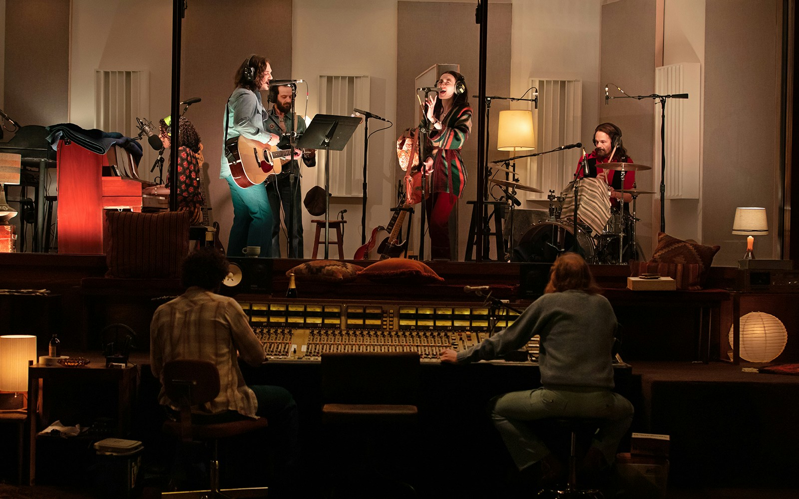 Musicians recording in a studio with guitars, drums, and sound equipment, related to Stereophonic.