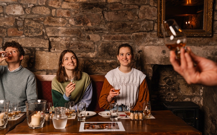 Guests enjoying whisky tasting at an underground tour in Edinburgh.