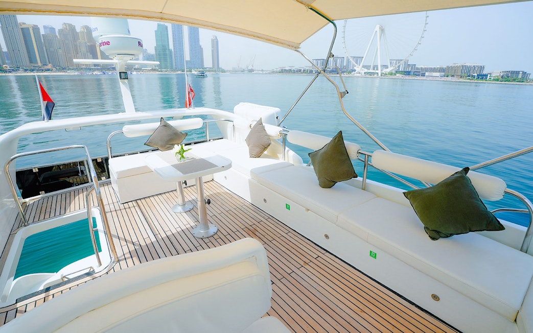 Luxury yacht deck with Dubai skyline and Ferris wheel in the background.