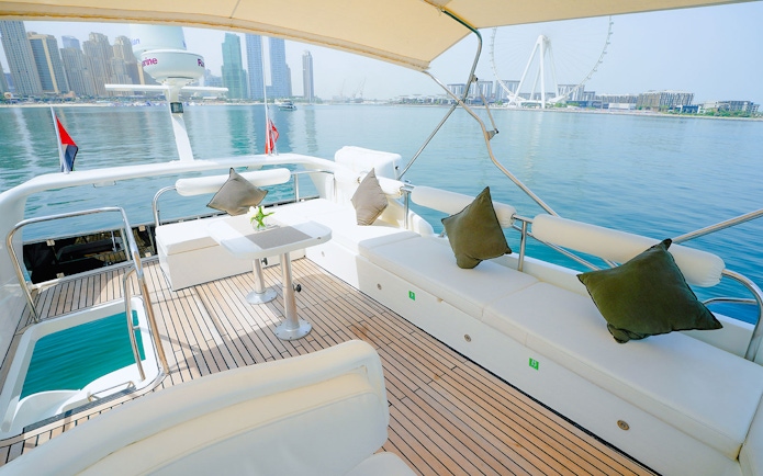 Luxury yacht deck with Dubai skyline and Ferris wheel in the background.