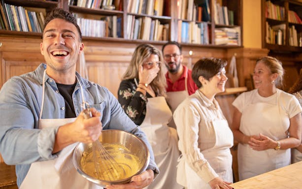 Group enjoying a pizza making class in Florence, mixing ingredients in a cozy kitchen setting.