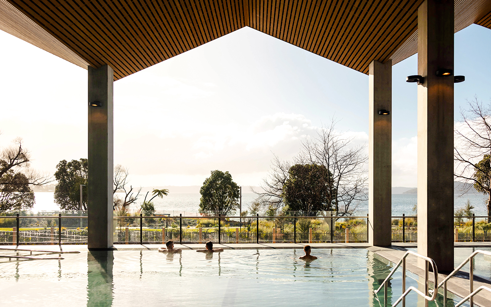 Wai Ariki Hot Springs & Spa indoor pool with lake view and visitors relaxing.